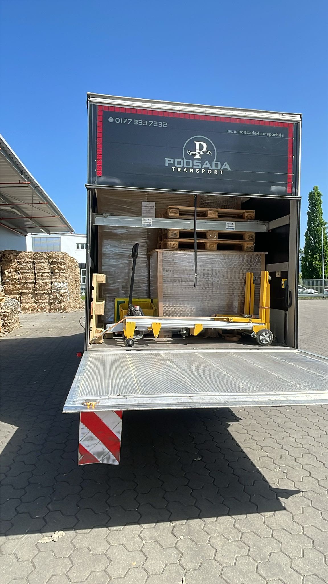 Interior of a Podsada Transport trailer loaded with pallets and a pallet jack