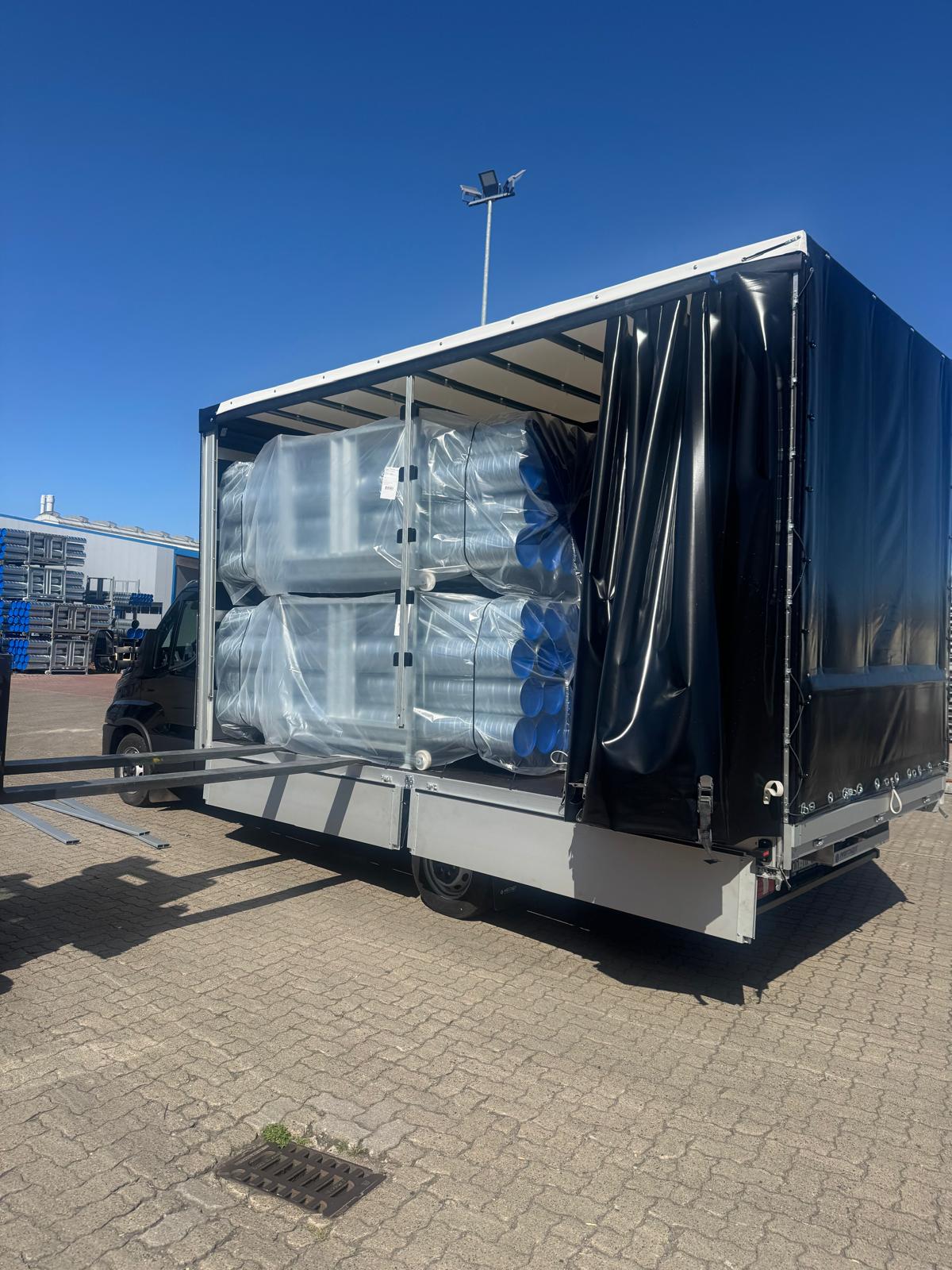 Trailer loaded with pipes and containers – industrial transport Germany